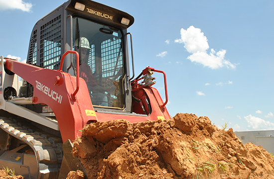 Man in a Takeuchi TL8 track loader pushing dirt on a construction site