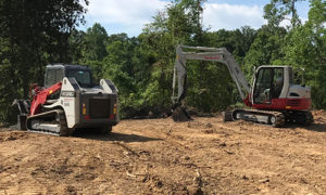Two Takeuchi Machines Being Used At A Jobsite